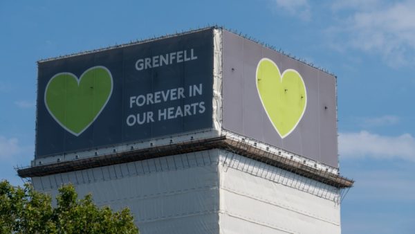 View of the Grenfell Tower covered in white wrapping and a green heart at the top, next to it reads 'Grenfell, forever in our hearts'. Fire Aware was created to prevent tragedies like Grenfell from happening again.