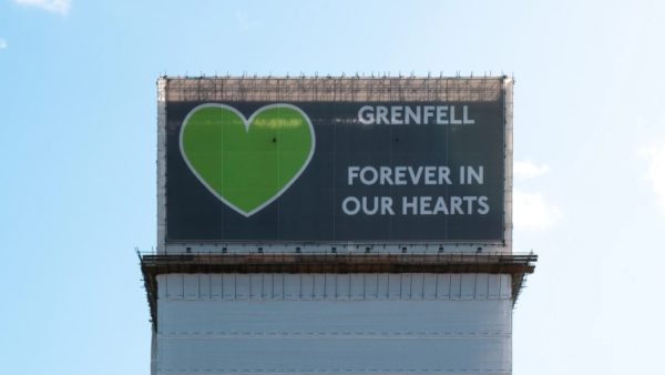 The remains of Grenfell Tower, covered in a wrap displaying a green heart with the words: