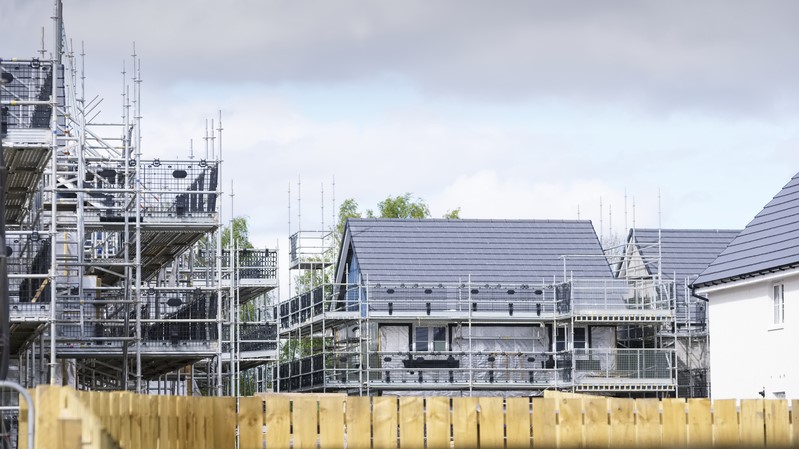 New houses under construction, covered in scaffolding