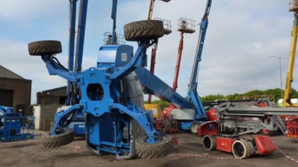 A blue genie machine toppled over on its side after the accident, with other MEWPs raised in the background