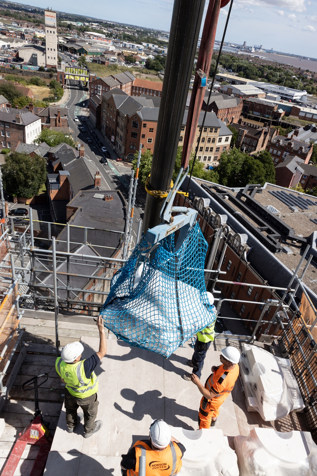 Three workers guide the stone putties into place on a specially built reinforced deck at Hull's Guildhall