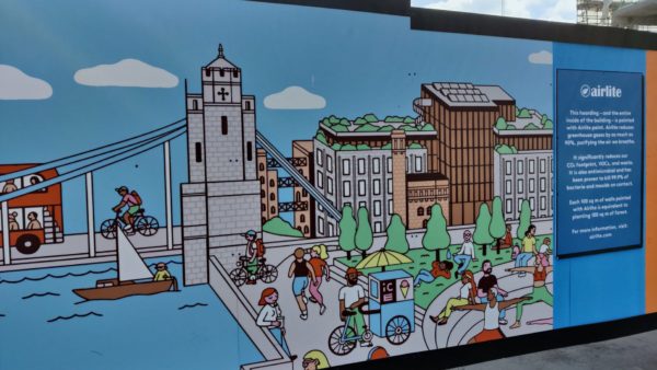 A hoarding with a painting of the Thames and Tower Bridge in London.
