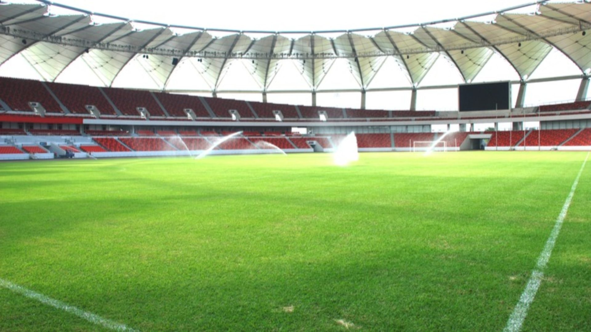 A green football pitch with self-irrigators spraying water.