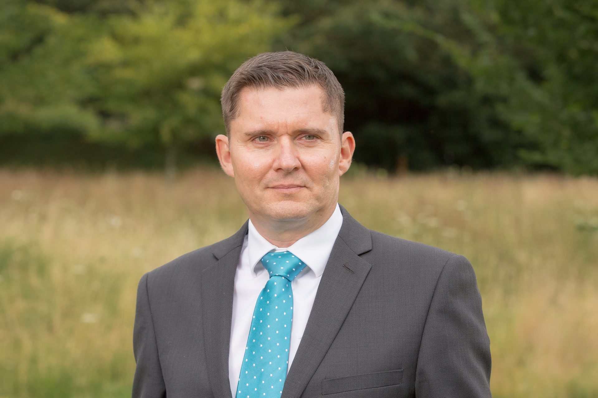 A man in a grey jacket and blue tie.