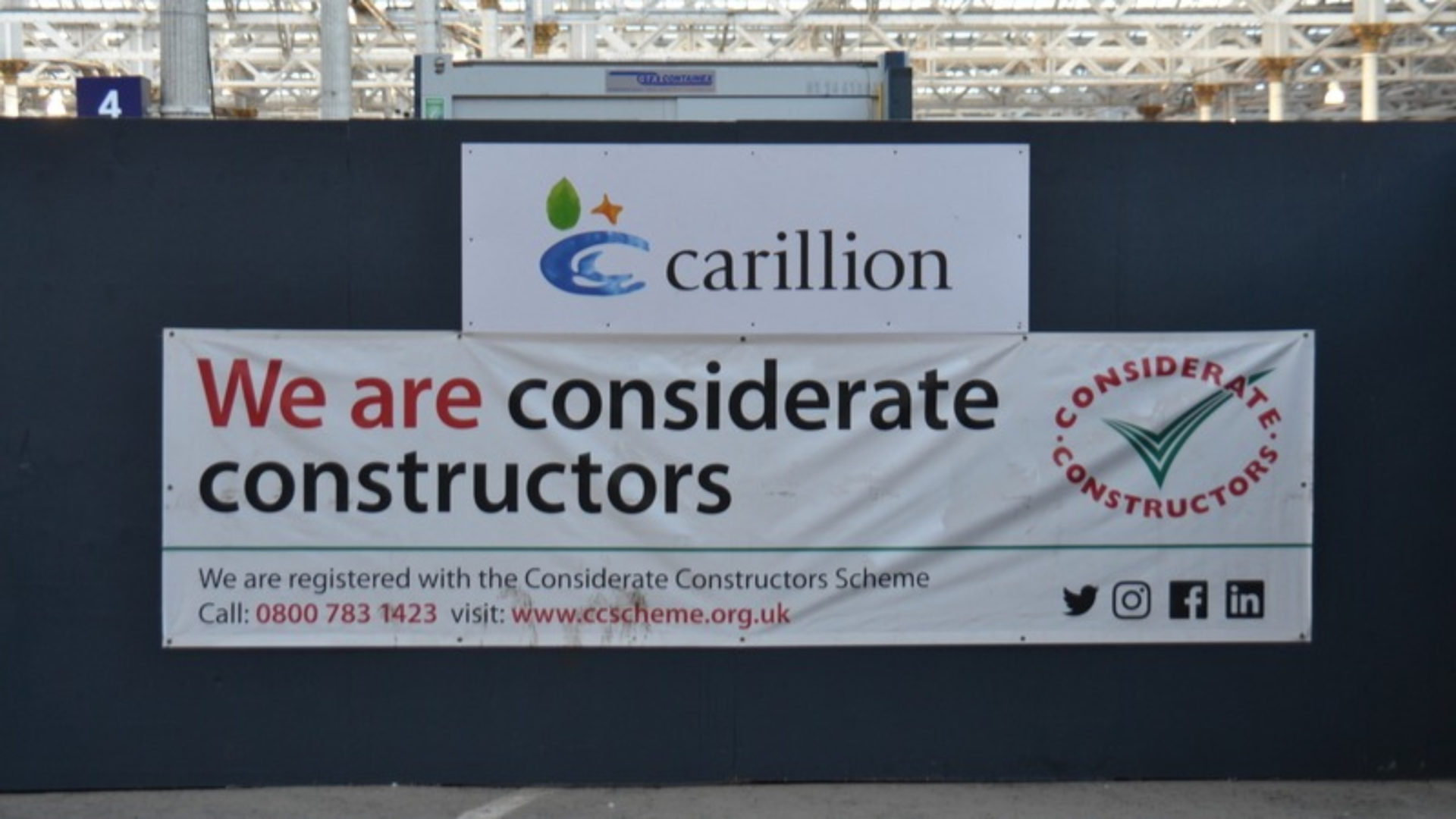 A construction hoarding with two banners, one that says Carillion and another that says we are considerate constructors. 