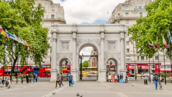 View of an old arch monument in a square with people.