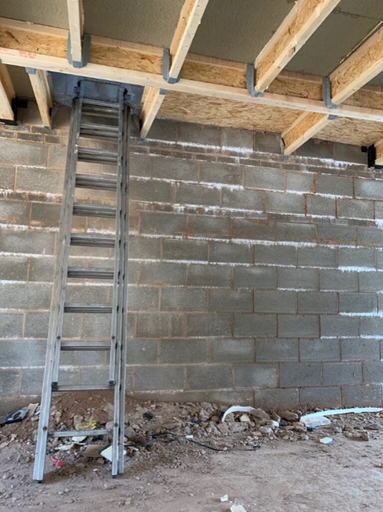 worker fractures skull A ladder on a building site with debris on the floor.