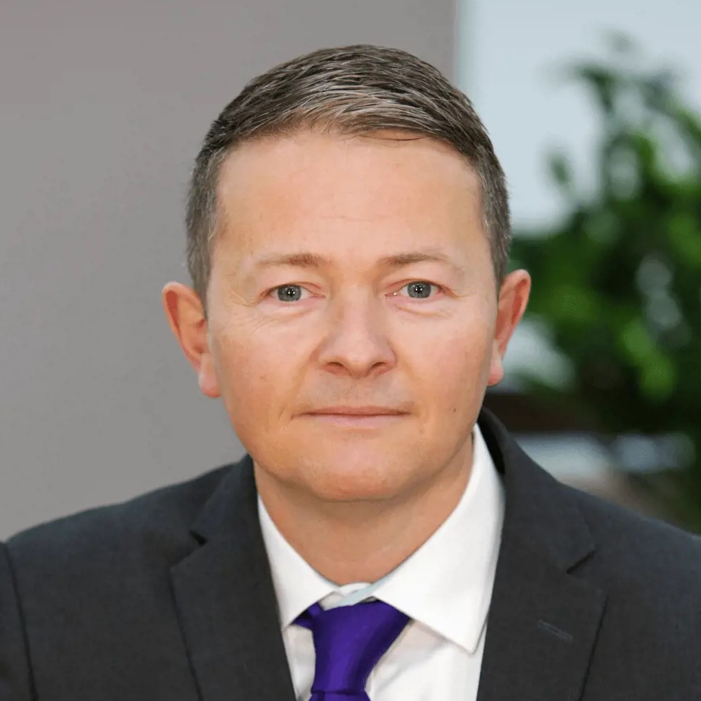 Mugshot of a man in a suit looking at the camera.