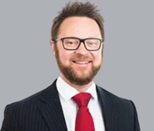 A man with glasses smiling at the camera.