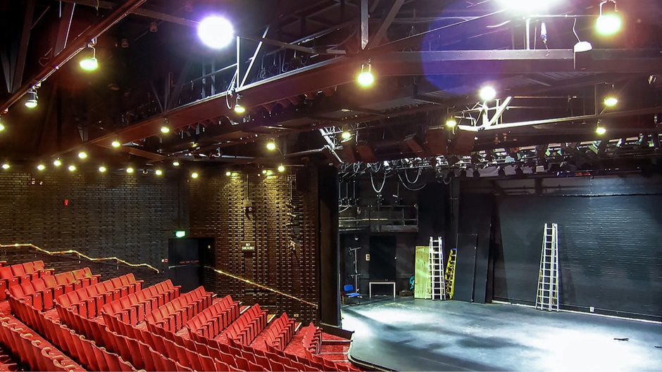 An empty theatre with red seats.