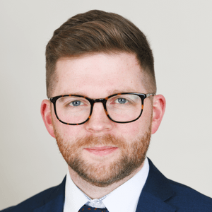 Mugshot of a man with glasses and beard looking at the camera.