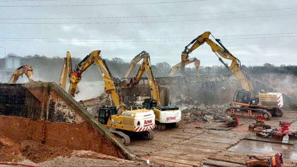 Excavators demolishing a bridge.