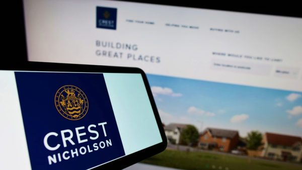 A mobile phone with a logo that says Crest Nicholson and a computer monitor in the background