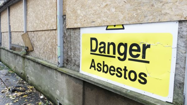 An asbestos danger sign at a building construction site - latest HSE data shows that the rate of work-related lung diseases is higher in construction