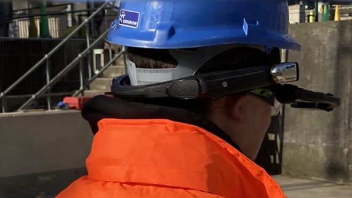 Back of a worker wearing an orange high-vis coat and blue hard hat - Digital Construction Awards: AtkinsRéalis entry for the Digital Innovation in Productivity award