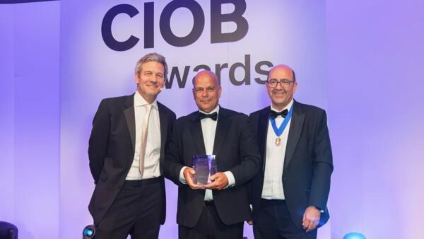Willmott Dixon's Jason Hunt (centre) receives the award from host Charlie Luxton (left) and CIOB president Mike Kagioglou (image: CIOB).
