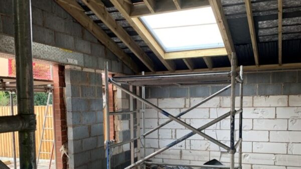 A house extension under construction, there's a scaffold and a big area where a window will be installed - two companies have been fined after a worker fell through the window gap.