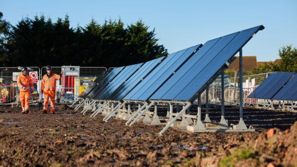 A line of solar panels on a construction site, with workers on the background - Kier has trialled its first solar and green hydrogen power solution to reduce carbon emissions on site
