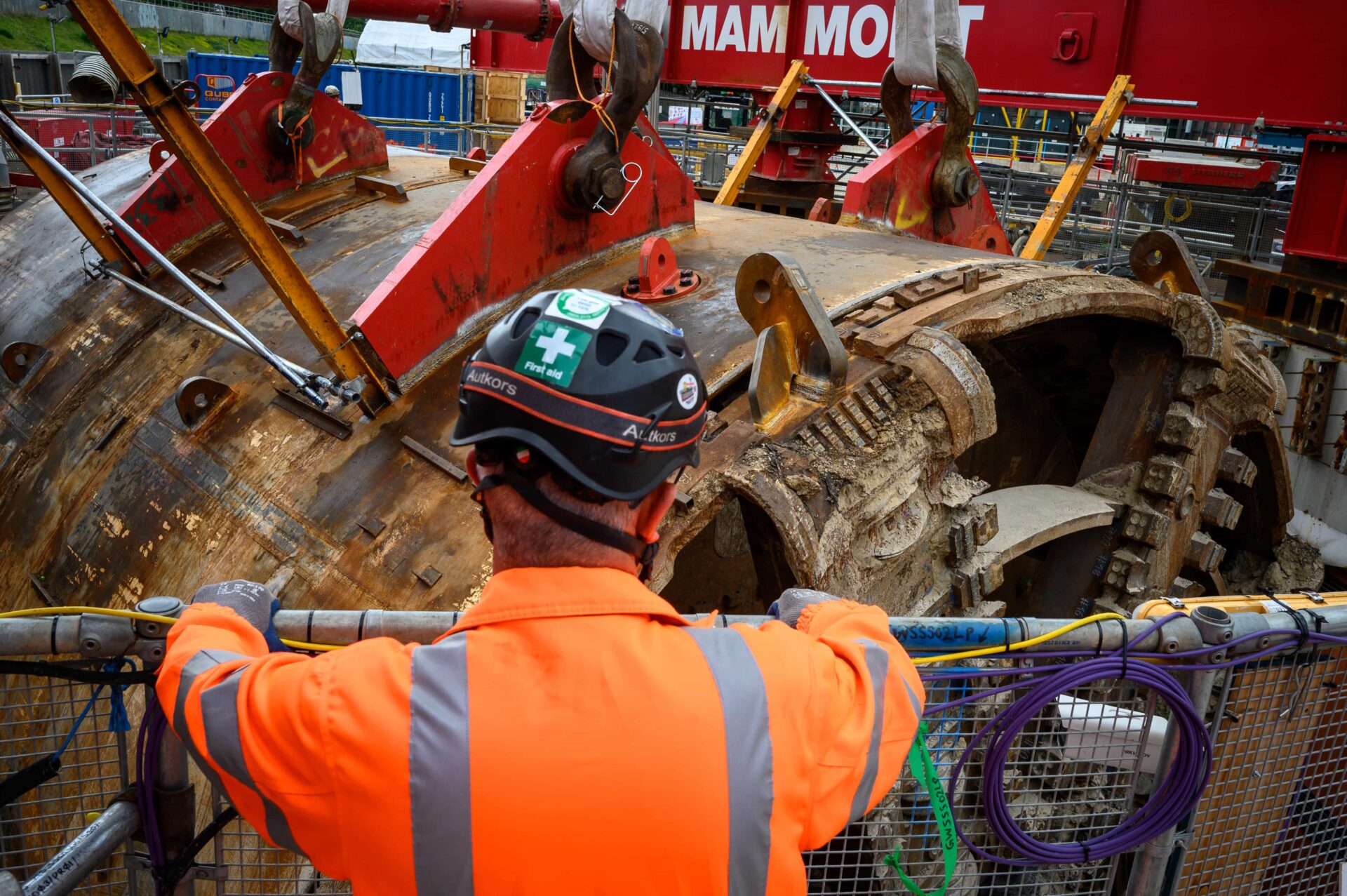 A giant boring tunnel machine and a construction worker in high-vis equipment and a hard hat