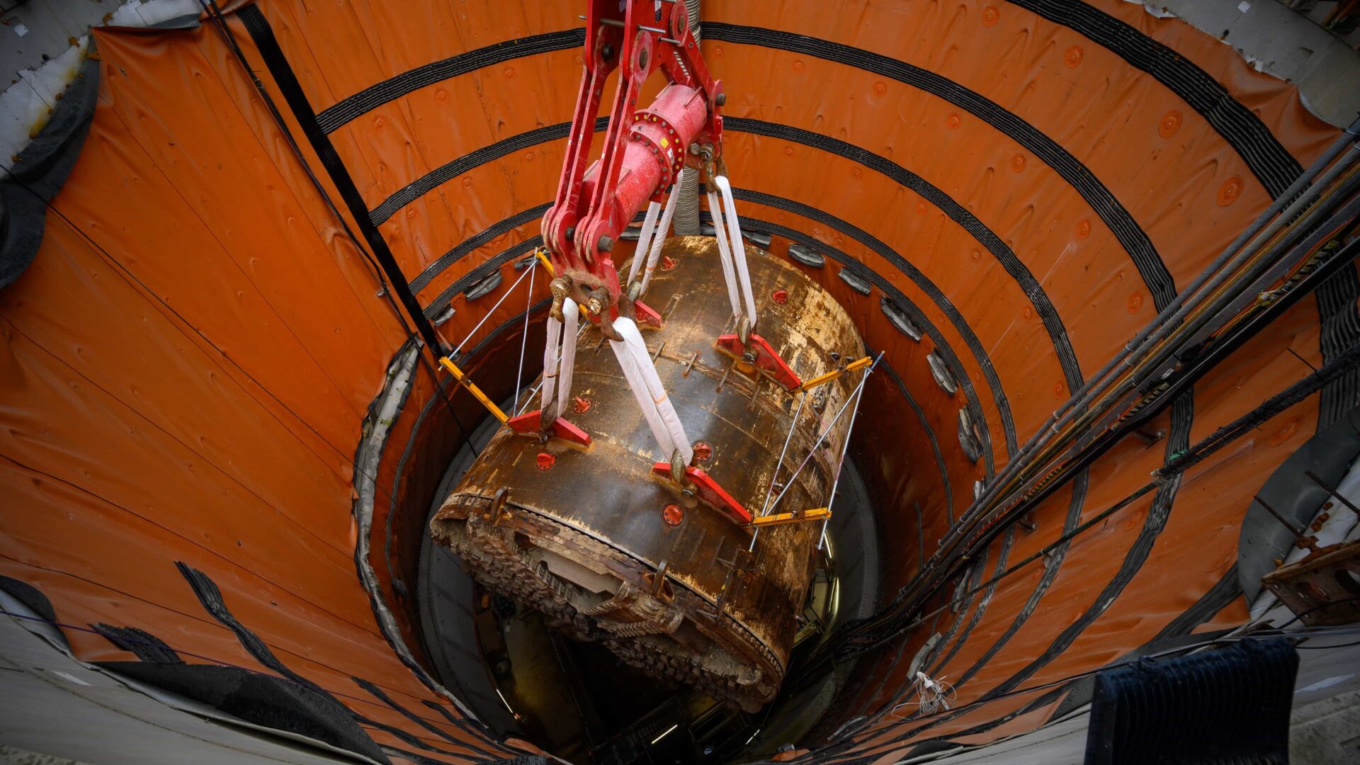A giant boring tunnel machine being lifted from a shaft