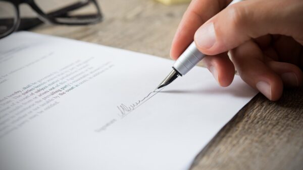 Hand holding a pen signing a document - the Construction Industry Council has signed the Conflict Avoidance Pledge