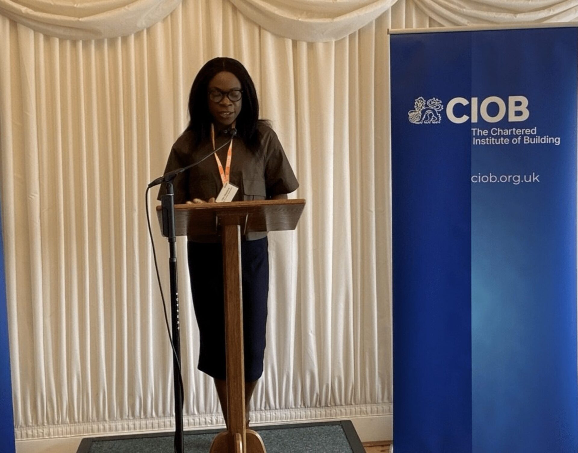 A woman at a lectern with a banner saying CIOB next to her - Source: CIOB PR Ola Obadara FCIOB appointed CIOB Vice President for 2025/26