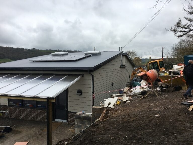 A construction site showing aggregate that's fallen over a wall under construction.